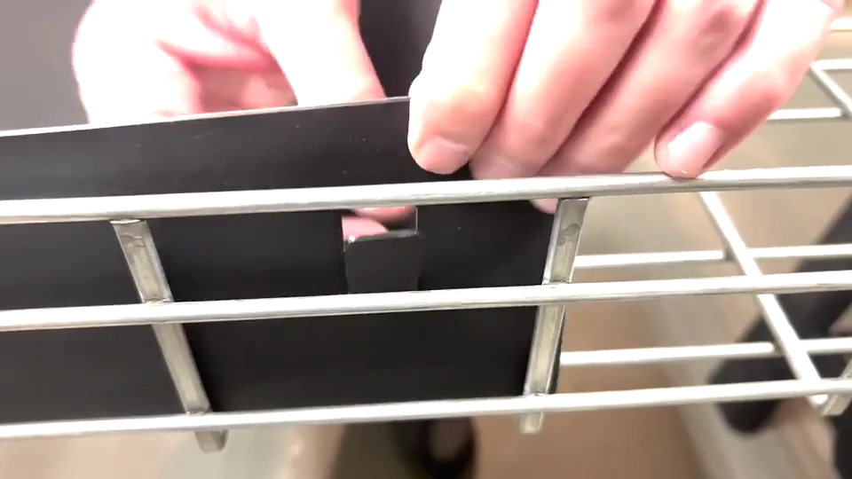 Close angled view of a hand fitting a tray liner into a wire basket