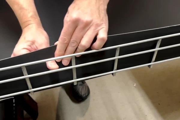 Close-up of hands engaging an integral locking tab with the basket wire.